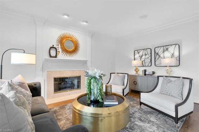 living area with ornamental molding, wood finished floors, and a high end fireplace