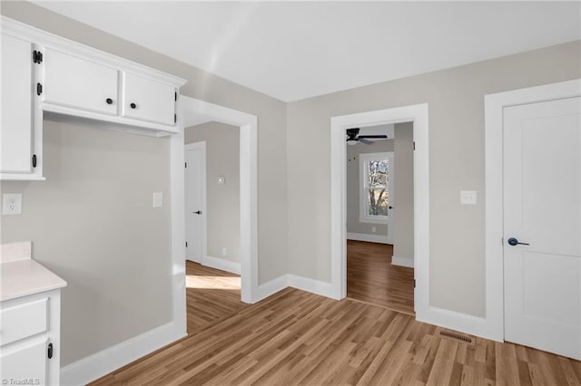 kitchen with white cabinetry, ceiling fan, and light hardwood / wood-style floors