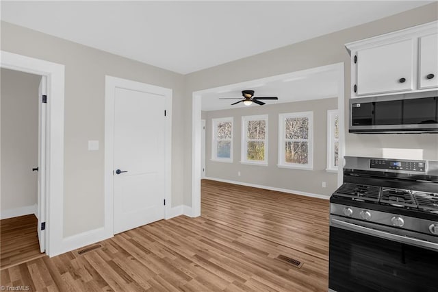 kitchen with stainless steel appliances, ceiling fan, white cabinets, and light wood-type flooring