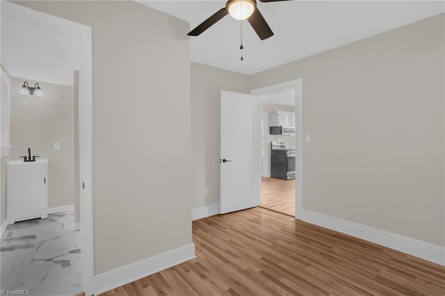 spare room with ceiling fan, sink, and light wood-type flooring