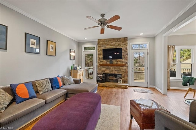 living room featuring a fireplace, ceiling fan, crown molding, and wood finished floors