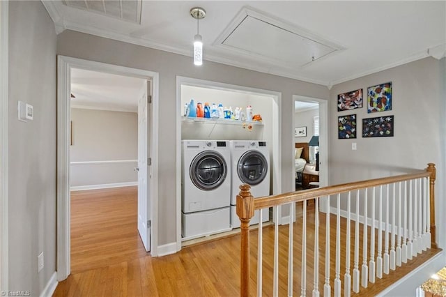 washroom with attic access, washer and clothes dryer, ornamental molding, and light wood-style floors