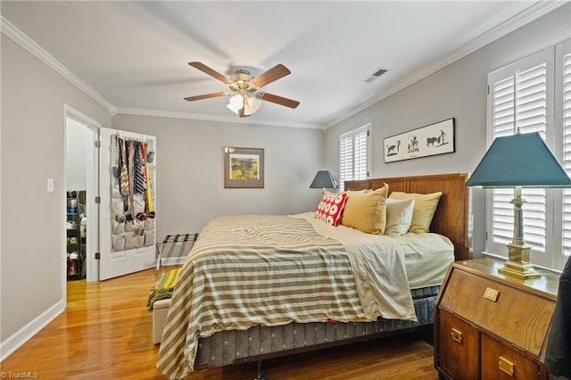 bedroom featuring visible vents, wood finished floors, baseboards, and ornamental molding