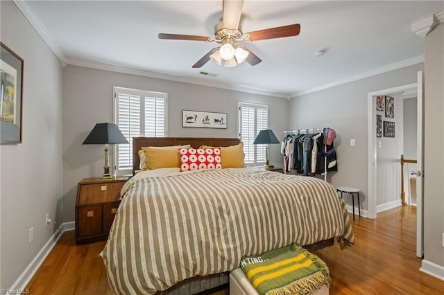 bedroom with baseboards, ornamental molding, visible vents, and wood finished floors