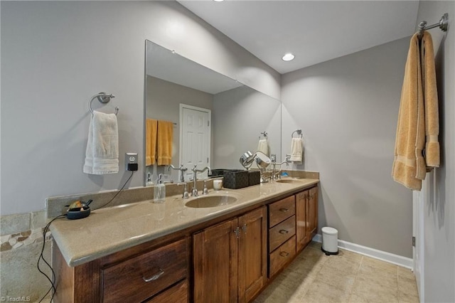 full bathroom with baseboards, double vanity, and a sink