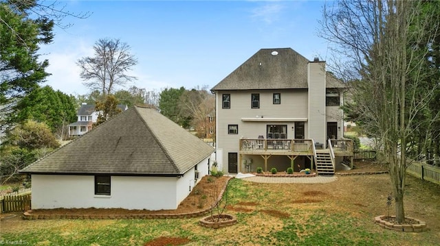 back of house featuring fence, a wooden deck, a yard, and a chimney