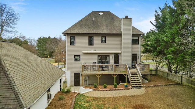 rear view of property featuring a chimney, a wooden deck, a fenced backyard, roof with shingles, and stairs
