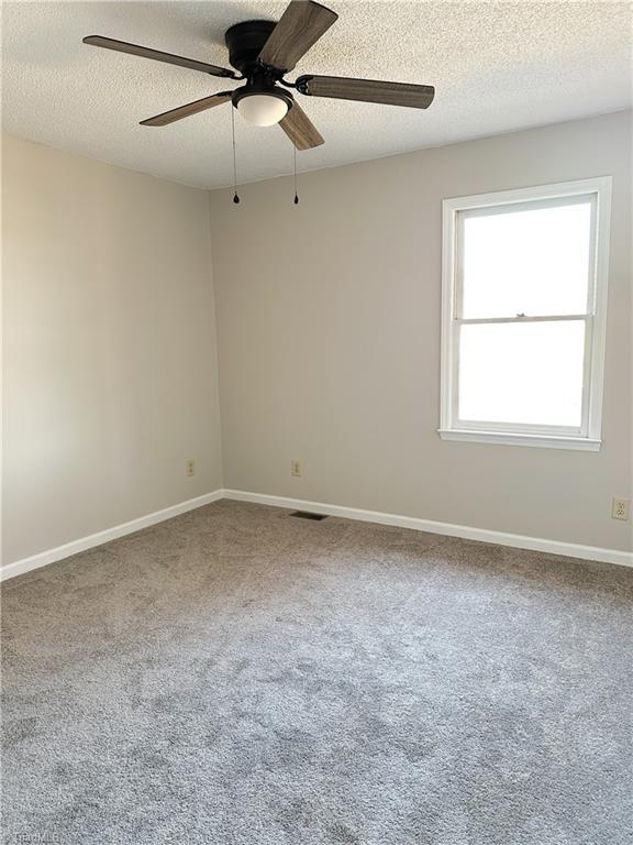 carpeted spare room with a textured ceiling and ceiling fan