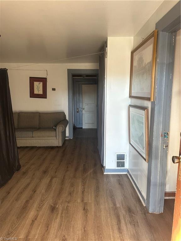 corridor with dark hardwood / wood-style floors and lofted ceiling