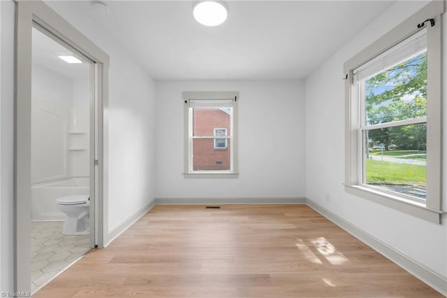 502 Eighth St, Mebane, NC 27302 - unfurnished bedroom featuring multiple windows and light wood-style flooring