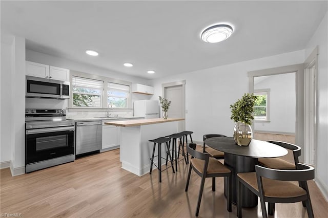 502 Eighth St, Mebane, NC 27302 - kitchen with appliances with stainless steel finishes, white cabinets, light wood-style floors, and recessed lighting