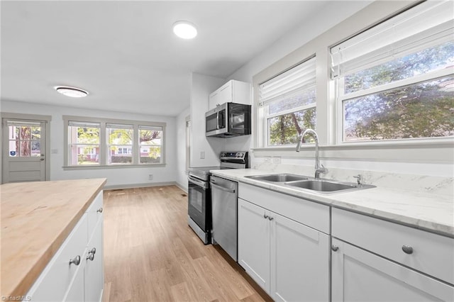 502 Eighth St, Mebane, NC 27302 - kitchen with appliances with stainless steel finishes, healthy amount of natural light, light wood-type flooring, and white cabinetry
