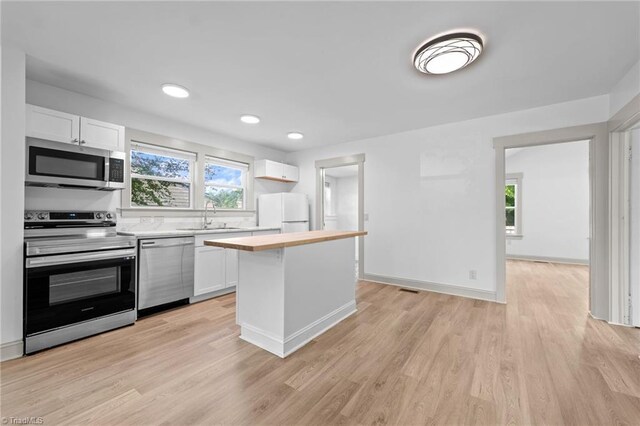 502 Eighth St, Mebane, NC 27302 - kitchen with appliances with stainless steel finishes, white cabinetry, a kitchen island, light wood-style flooring, and recessed lighting