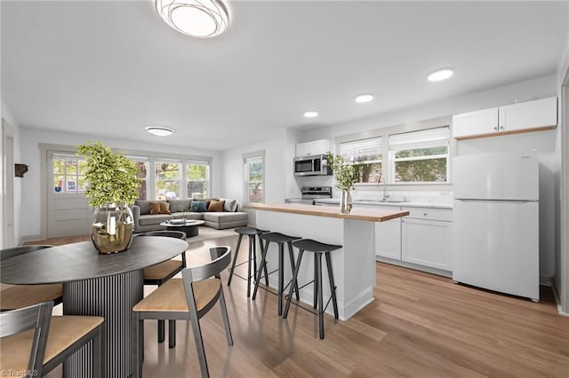 502 Eighth St, Mebane, NC 27302 - kitchen with stainless steel appliances, a kitchen bar, white cabinetry, light wood-type flooring, and recessed lighting