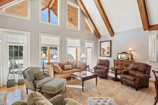 living room with high vaulted ceiling, beamed ceiling, and light hardwood / wood-style flooring