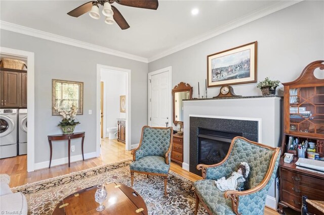 sitting room featuring crown molding, separate washer and dryer, light wood-type flooring, and ceiling fan