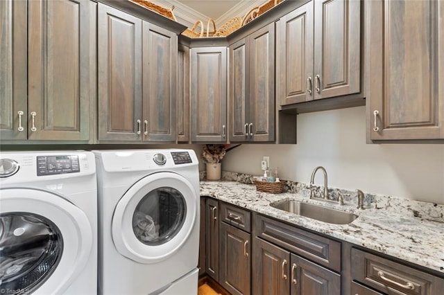 laundry room featuring sink, crown molding, washing machine and clothes dryer, and cabinets