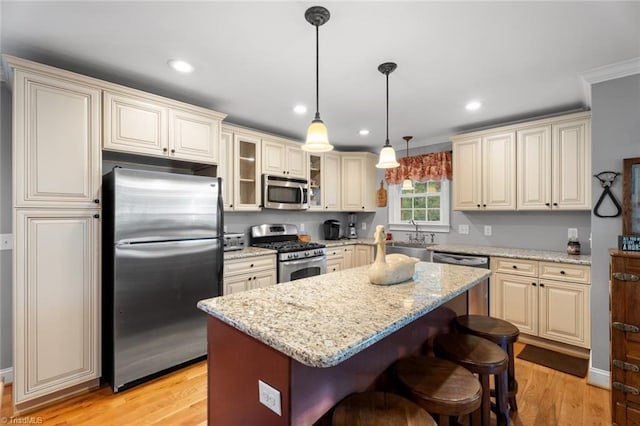 kitchen featuring stainless steel appliances, a breakfast bar area, light hardwood / wood-style flooring, and a kitchen island