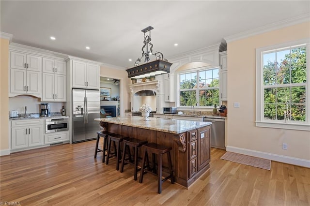 kitchen featuring plenty of natural light, appliances with stainless steel finishes, a center island, and light wood-type flooring