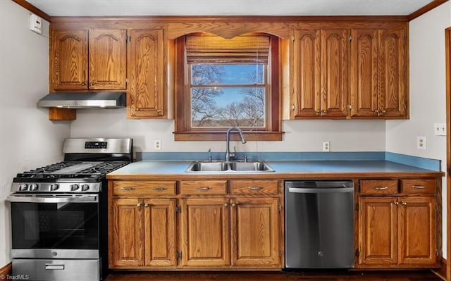 kitchen with appliances with stainless steel finishes, brown cabinets, under cabinet range hood, and a sink