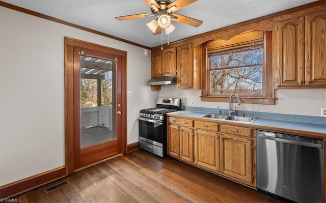 kitchen with visible vents, under cabinet range hood, ornamental molding, stainless steel appliances, and a sink