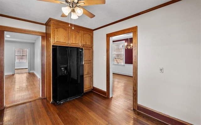 kitchen featuring ornamental molding, black fridge with ice dispenser, dark wood finished floors, brown cabinetry, and baseboards