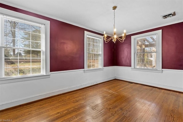 unfurnished dining area featuring an inviting chandelier, wood finished floors, visible vents, and a healthy amount of sunlight