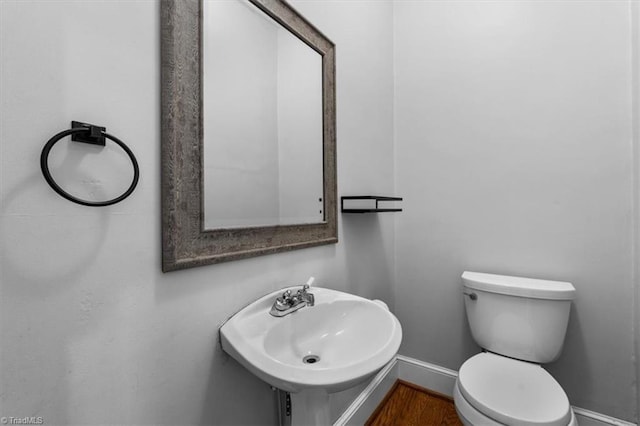 bathroom featuring wood finished floors, toilet, baseboards, and a sink