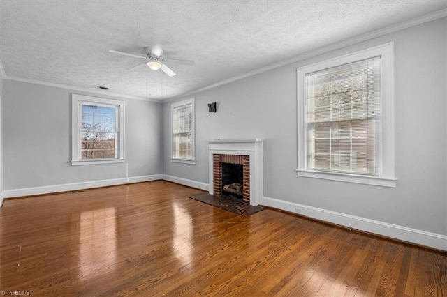 unfurnished living room with wood finished floors, baseboards, a fireplace, ornamental molding, and a textured ceiling