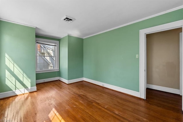 empty room featuring baseboards, ornamental molding, and hardwood / wood-style flooring