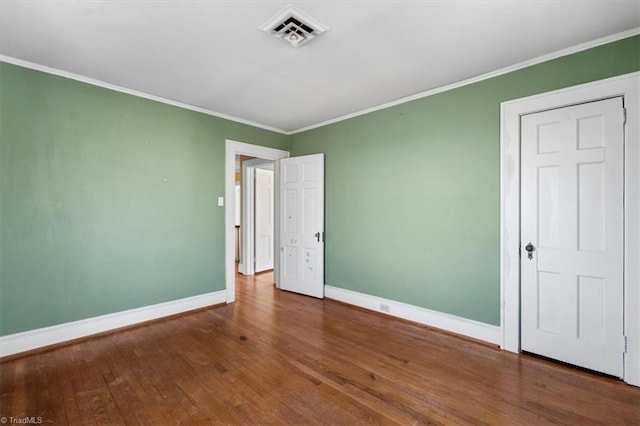 unfurnished bedroom featuring visible vents, crown molding, baseboards, and wood finished floors