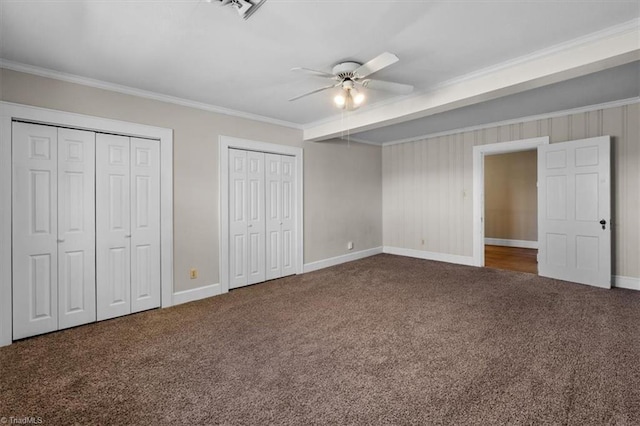 unfurnished bedroom featuring baseboards, carpet, multiple closets, and ornamental molding