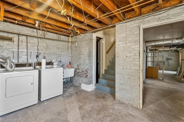 unfinished below grade area featuring washer and dryer, brick wall, and stairs