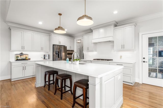 kitchen featuring sink, a kitchen island with sink, white cabinetry, stainless steel refrigerator with ice dispenser, and decorative light fixtures