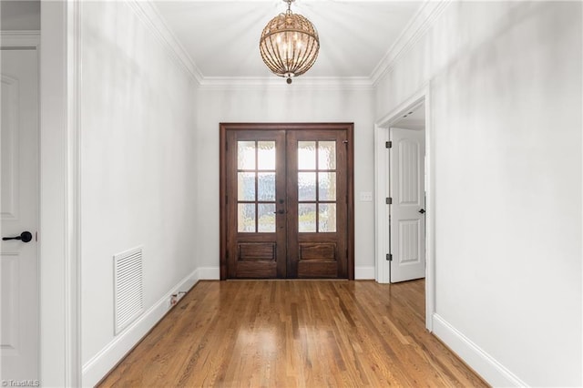 entryway featuring crown molding, a chandelier, light wood-type flooring, and french doors