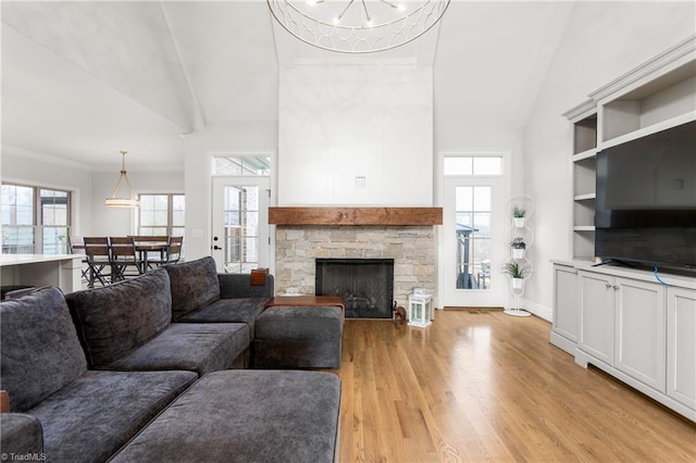 living room featuring a fireplace, crown molding, light hardwood / wood-style flooring, and a healthy amount of sunlight