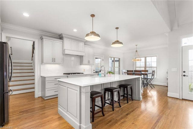 kitchen featuring stainless steel refrigerator, decorative light fixtures, sink, a kitchen island with sink, and gas stovetop