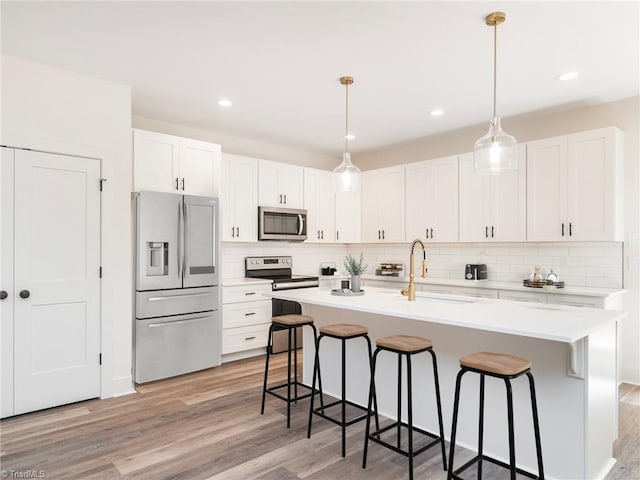 kitchen featuring appliances with stainless steel finishes, a kitchen breakfast bar, light countertops, light wood-style floors, and a sink