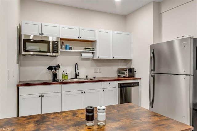 kitchen with white cabinetry, appliances with stainless steel finishes, wooden counters, and a sink