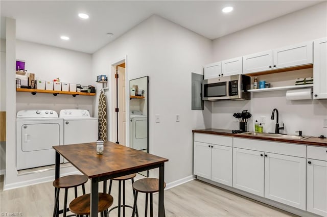 kitchen with open shelves, light wood-style flooring, a sink, stainless steel microwave, and independent washer and dryer