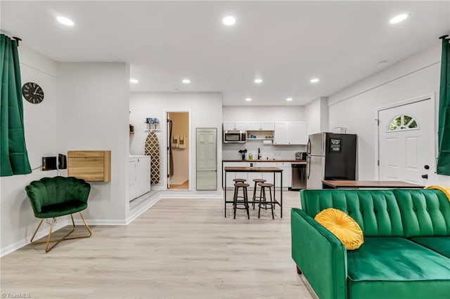 living room with recessed lighting, baseboards, and light wood finished floors