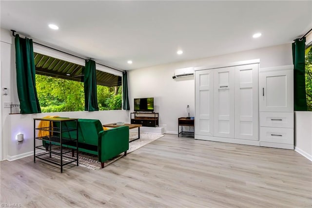 living area with a wall mounted air conditioner, light wood-style floors, a healthy amount of sunlight, and recessed lighting