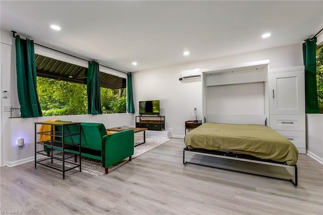 bedroom with a wall mounted air conditioner, wood finished floors, and recessed lighting