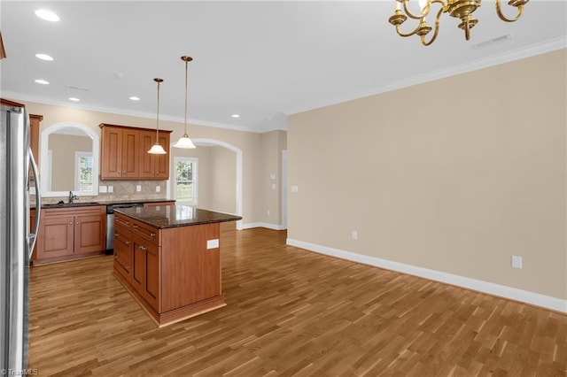 kitchen with stainless steel appliances, tasteful backsplash, wood-type flooring, a kitchen island, and decorative light fixtures