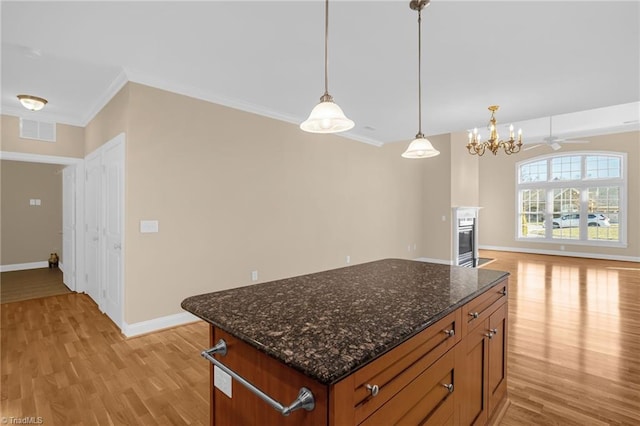 kitchen with crown molding, a kitchen island, hanging light fixtures, and light hardwood / wood-style flooring