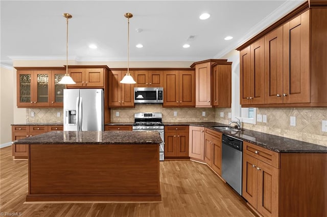 kitchen featuring hanging light fixtures, stainless steel appliances, a center island, and dark stone counters