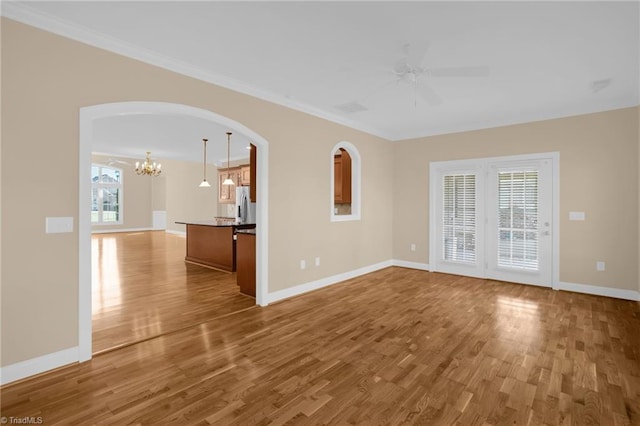 unfurnished living room with hardwood / wood-style flooring, a healthy amount of sunlight, and ceiling fan with notable chandelier