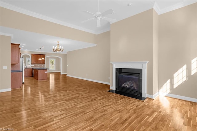 unfurnished living room featuring crown molding, ceiling fan with notable chandelier, and light hardwood / wood-style flooring