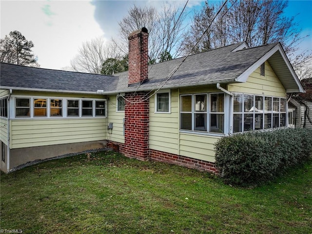 rear view of property featuring a lawn and a sunroom