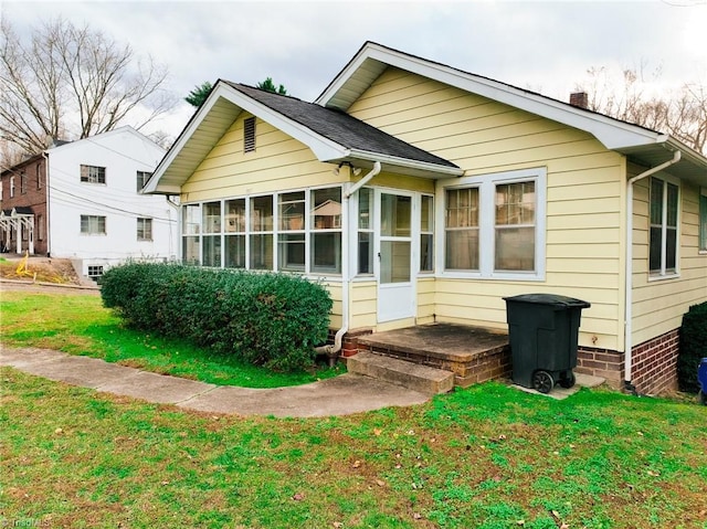 back of property with a lawn and a sunroom